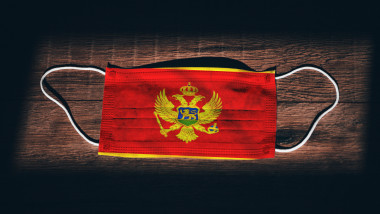 Montenegro National Flag at medical, surgical, protection mask on black wooden background. Coronavirus Covid"u201319, Prevent infection, illness or flu. State of Emergency, Lockdown...