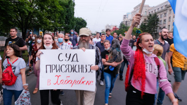 oameni mărșăluiesc protestând cu pancarte și steaguri în Rusia