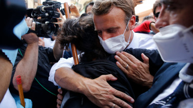 Președintele francez Emmanuel Macron îmbrățișează o locuitoare din Beirut în timpul vizitei din 6 august făcute după explozia devastatoare din portul capitalei libaneze