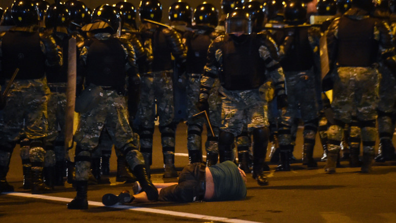 Un bărbat zace pe jos în fața forțelor de ordine în timpul protestului care a izbucnit la Minsk după închiderea urnelor în scrutinul prezidențial din 9 august 2020