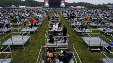 spectatorii pastreaza distantarea fizica la un concert in aer liber stand pe platforme metalice