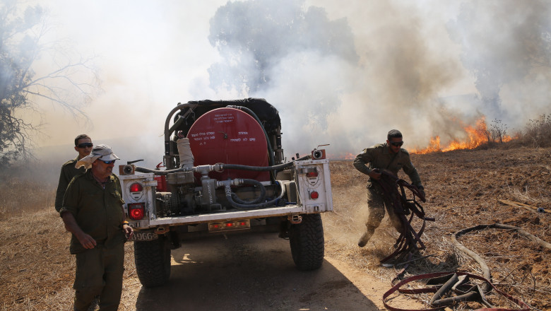 Soldați israelieni încercând să stingă incendiile de vegetație provocate de baloanele incendiare trimise peste graniță de Hamas