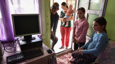 copii saraci se uita la un computer nou primit de la un ong
