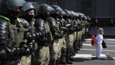O protestatară din Minsk îngenunchează în fața forțelor de ordine în timpul protestelor masive din Belarus.