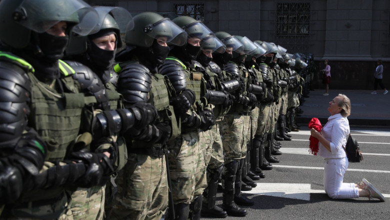 O protestatară din Minsk îngenunchează în fața forțelor de ordine în timpul protestelor masive din Belarus.
