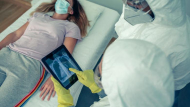 Pacient suspect de coronavirus pe patul de spital având alături cu un medic care analizează o radiografie pulmonară