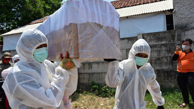 Angajați care poartă combinezoane de protecție transportă un fals sicriu pe străzile din Jakarta ca parte a campaniei de conștientizare a riscurilor din pandemia de COVID-19