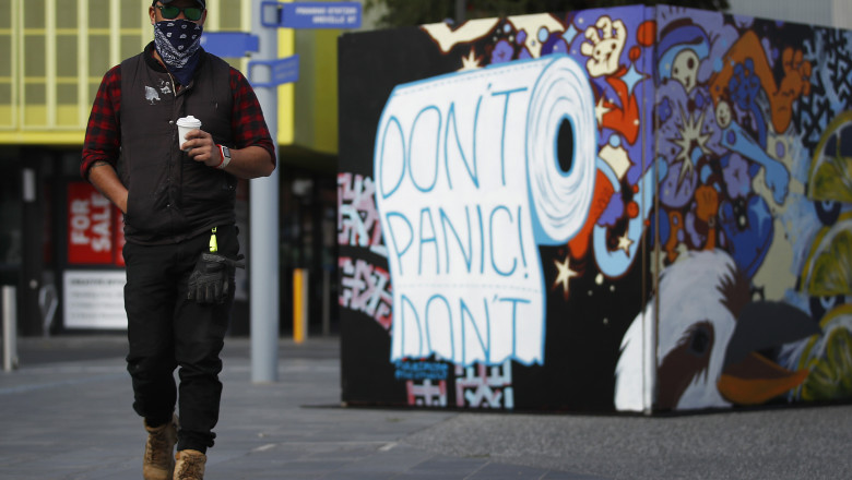 Un bărbat din Melbourne trece pe lângă un grafitti cu mesajul „Nu te panica!” Foto: GettyImages