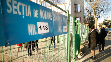 indicatoare sectii de votare puse pe gardul unei institutii si alegatori