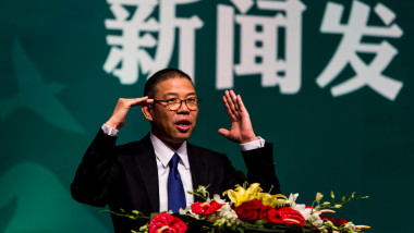 miliardarul Zhong Shanshan tine un discurs de la o tribuna cu flori