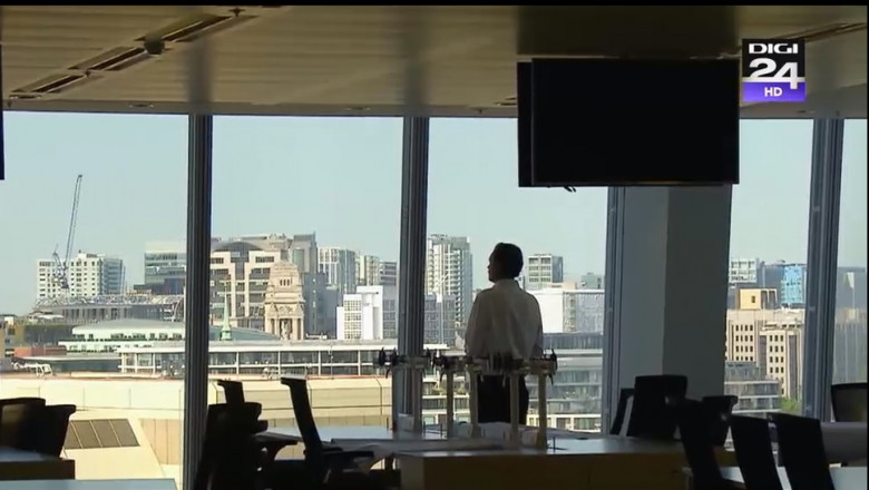 barbat singur in birou uitandu-se pe fereastra
