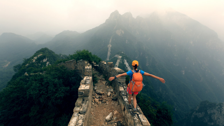 successful woman hiker open arms to the great wall on the top of mountain