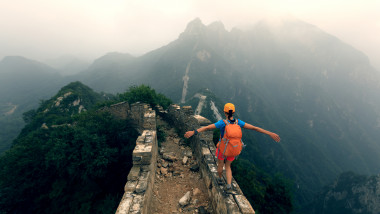 successful woman hiker open arms to the great wall on the top of mountain