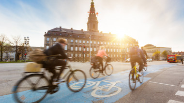 Oamenii preferă să meargă pe bicicletă prin Copenhaga. În fundal este Palatul Christiansborg
