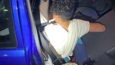 Copil de 13 ani ascuns pe bancheta din spate a unei mașini, acoperit cu bagaje