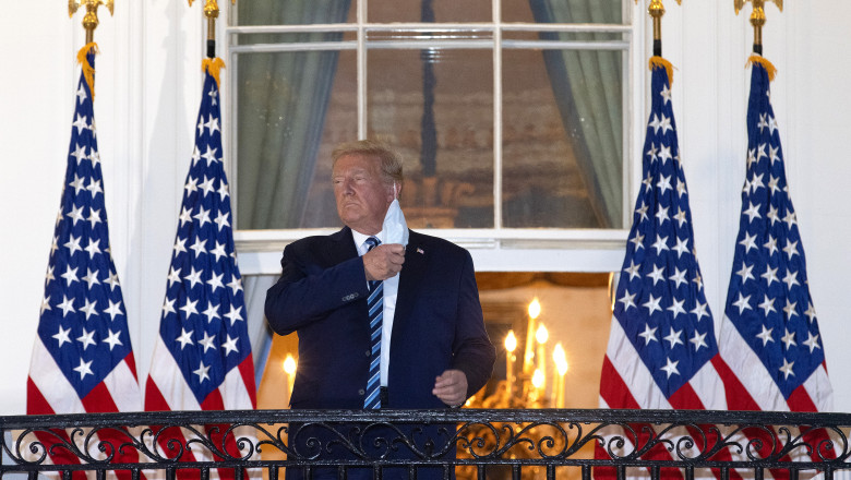 Donald Trump, bolnav de Covid-19, stă la balconul Casei Albe în timp ce își dă jos masca de protecție.