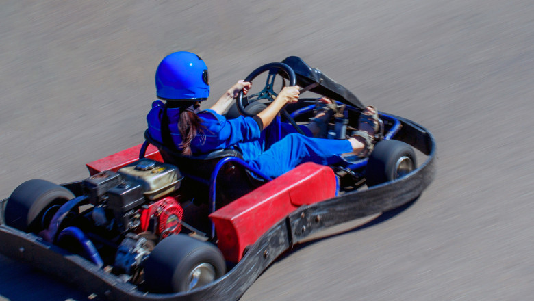 Karting on racing round in the open air. Woman behind the wheel of a kart. Girl rides on a kart with high speed.