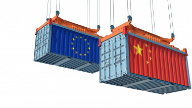 un container albastru cu steagul UE si un container rosu cu steagul chinei, ridicate de o macara