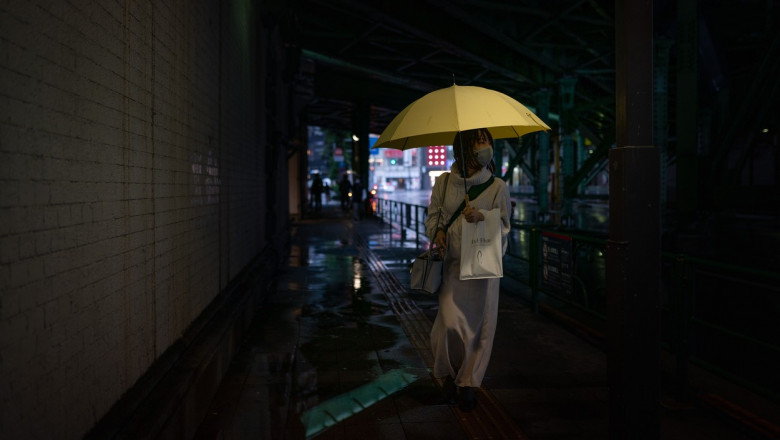 O femeie cu umbrelă în timpul ploilor abundente aduse de venirea taifunului Chan-hom.