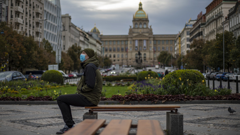 Un barbat cu masca se odihneste pe o banca, in centrul orasului Praga