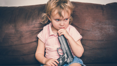 Un copil se joacă cu arma părinților