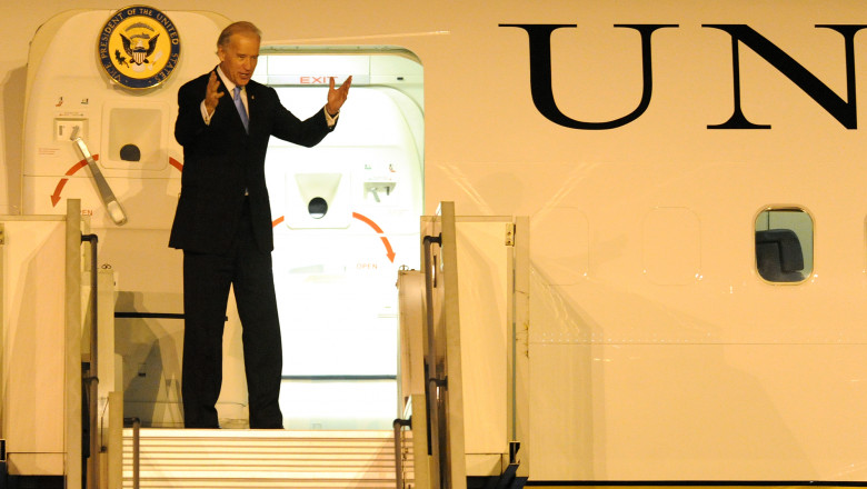 Joe biden pe scara avionului de vicepresedinte al sua, cu mainile ridicate, vesel