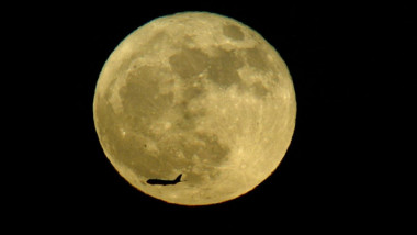 avion traverseaza cerul prin fata lunii