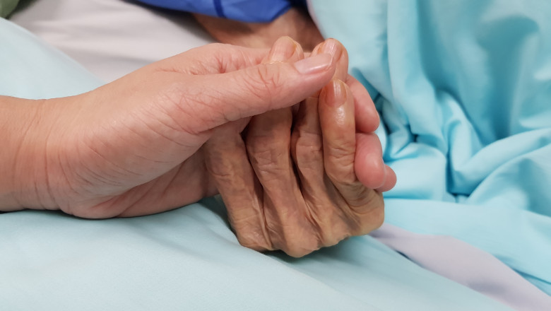 Femeie ținută de mână pe patul de spital