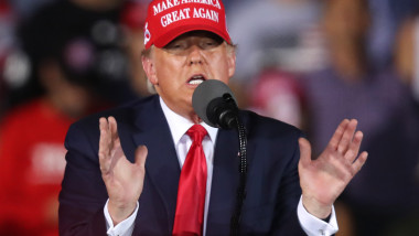 Donald Trump, cu o șapcă MAGA, vorbește tribună în timpul unui miting electoral în statul Florida.