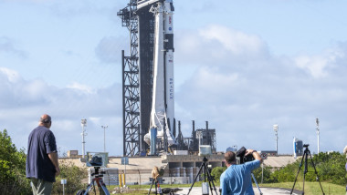 Un aligator începe să traverseze drumul în timp ce fotografii și operatorii își pregăteau echipamentele pentru a lua imagini de la pregătirea pentru lansare a rachetei Falcon 9 a SpaceX care va lansa sâmbătă capsula Crew Dragon cu patru astronauți la bord de la Cape Canaveral, Florida