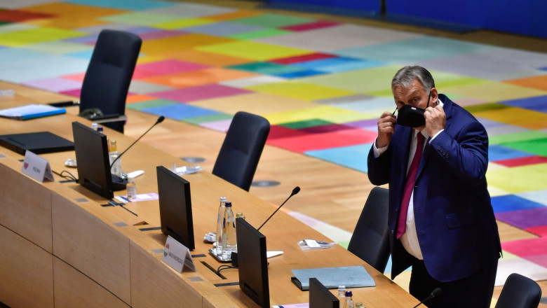 Viktor Orban, premierul Ungariei, singur la masa Consiliului European, își ajustează masca de protecție.