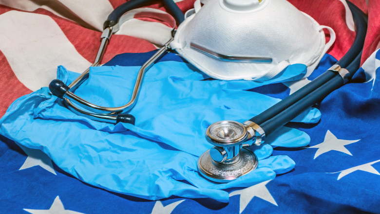 O mască de protecție, un stetoscop și o pereche de mânuși de protecție pe un steag al Statelor Unite. Ilustrație pandemie coronavirus