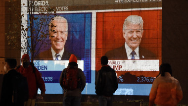 americani se uita la un ecran cu rezultatele alegerilor prezidentiale SUA 2020, cu scorurile obtinute de Donald Trump şi Joe Biden
