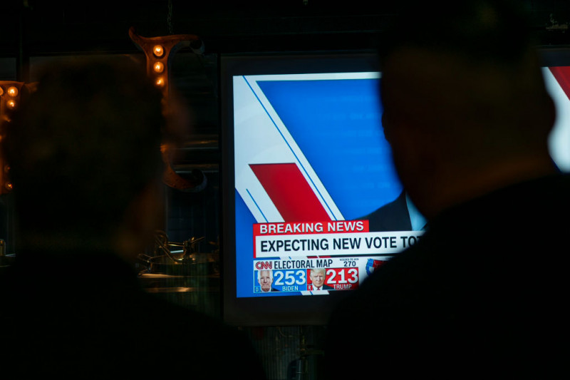 Oameni în bar se uită la televizor la ultimele ştiri despre rezultatul alegerilor prezidenţiale din SUA 2020