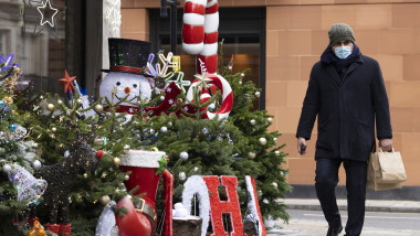 Sărbători de iarnă în mijlocul pandemiei de Coronavirus. Un bărbat cu mască de protecție merge pe stradă pe lângă decorațiuni de Crăciun.