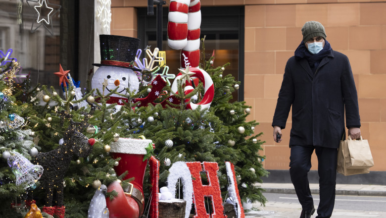 Sărbători de iarnă în mijlocul pandemiei de Coronavirus. Un bărbat cu mască de protecție merge pe stradă pe lângă decorațiuni de Crăciun.
