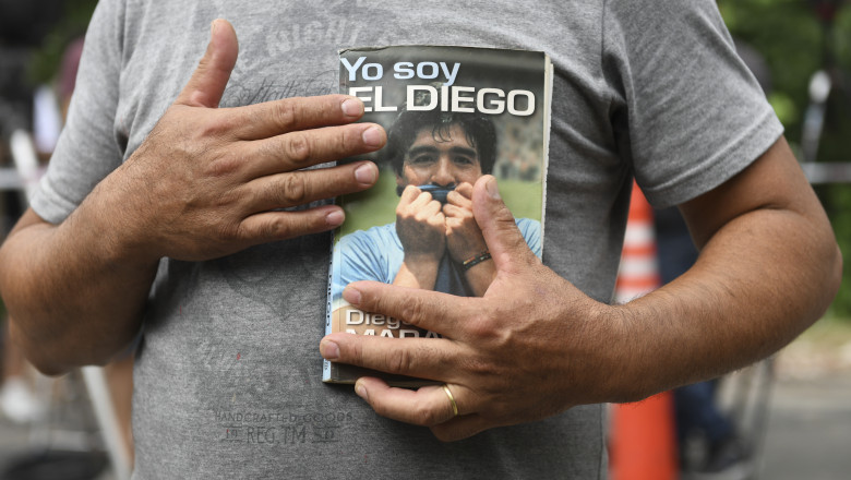 Un fan al lui Diego Maradona ține la piept cartea acestuia de memorii „Eu sunt Diego”