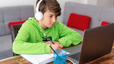 baiat in fata unui laptop face scoala online