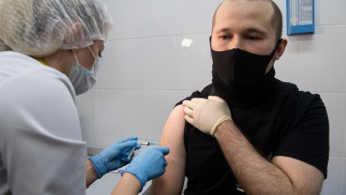 barbat care priveste vaccin anticovid