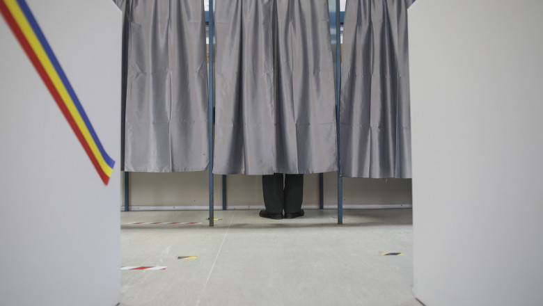 un barbat voteaza in cabina de vot