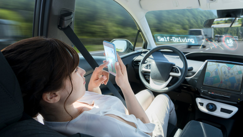 femeie se uita pe telefon intr-o masina autonoma care se conduce singura
