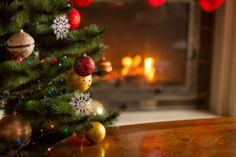 Closeup image of golden baubles on Christmas tree at fireplace