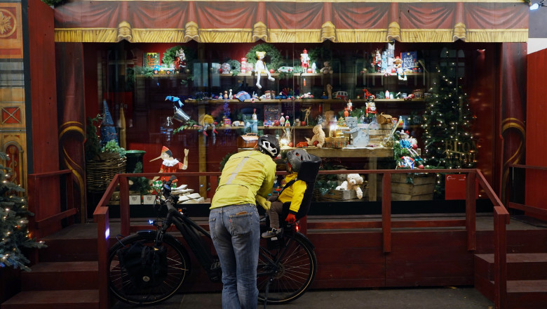adult si copil langa cu bicileta in fata unui magazin cu decoratiuni de craciun