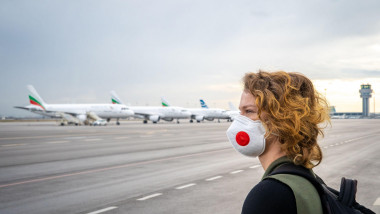 femeie cu masca pe aeoport cu avioane pe pista pe fundal