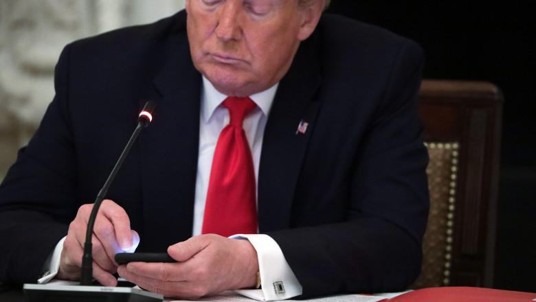 Donald Trump se uită pe telefon în timpul unei recepții la Casa Albă