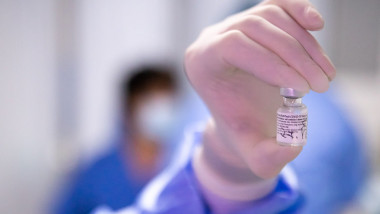 doza de vaccin tinuta in mana de un medic roman