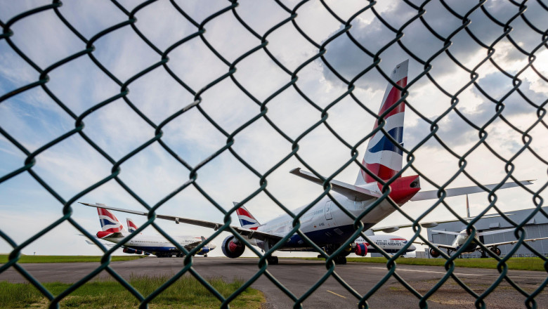 Seen through a wire fence, British Airways aeroplanes are parked at Cardiff Airport whilst unused during the Covid-19 crises.