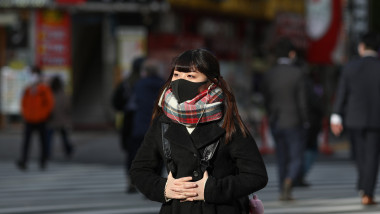 Fată purtând mască de protectiepentru a se feri de virusul Covid-19, pe strzile orașului Tokyo