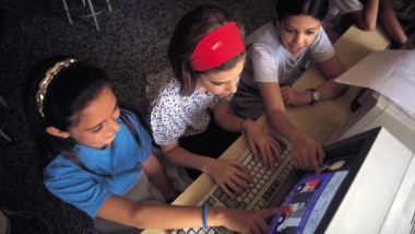 Niñas manejando un ordenador Three girls manage a computer during computer science class in a school of Madrid