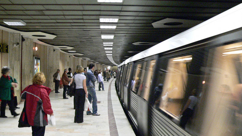 Stație de metrou în București cu oameni care asteapta pe peron in timp ce trenul ajunge în stație
